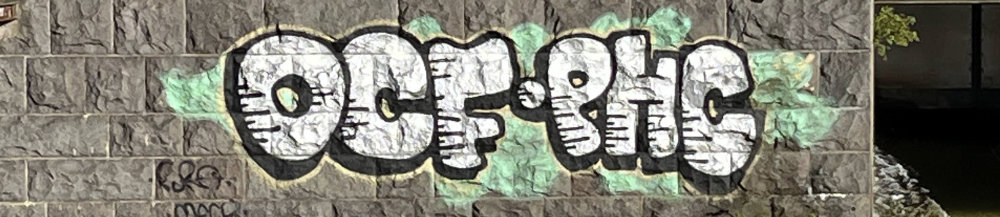 graffiti on black brick wall with the text "OCF PHC"